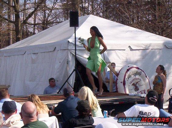 Woman in green dress on stage with a tent and audience