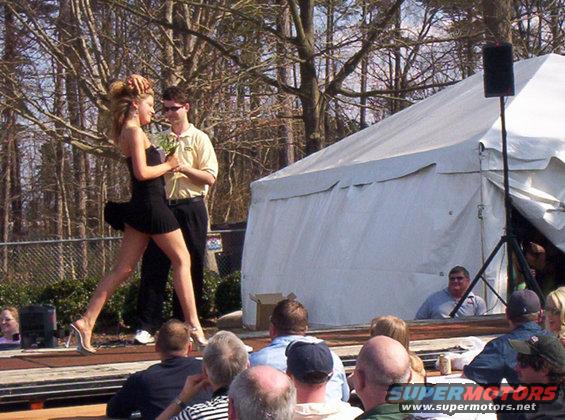 People gathered outdoors for an event with a tent and a stage