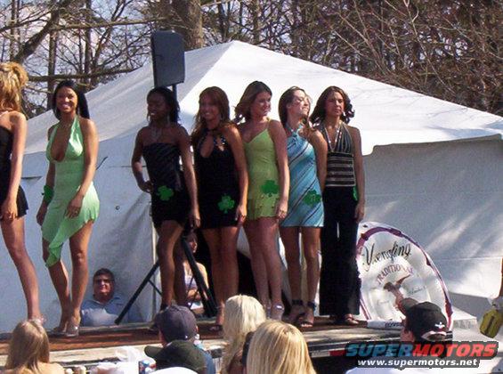 Women in dresses on a stage with a tent behind them