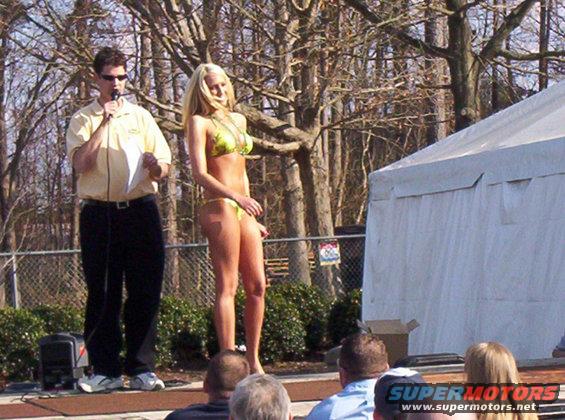 man with microphone next to woman in bikini on outdoor stage
