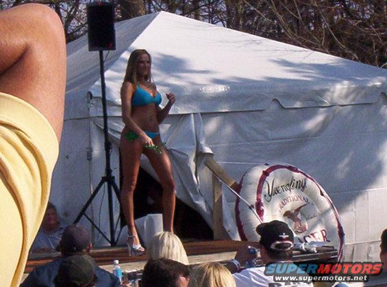 Bikini contest stage with a woman in a blue bikini and a large inflatable ring