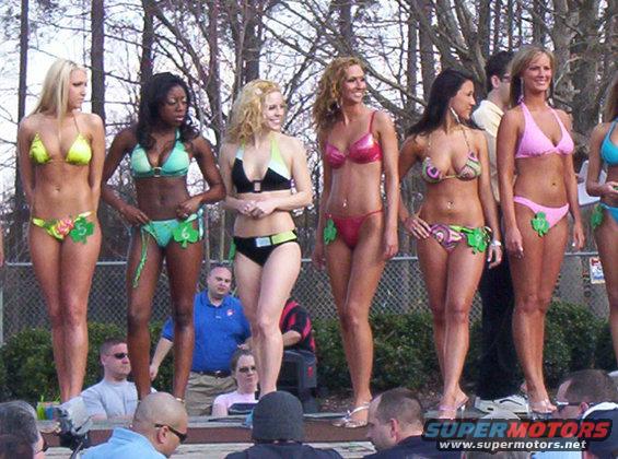 Women in bikinis stand on a stage with shamrock decorations