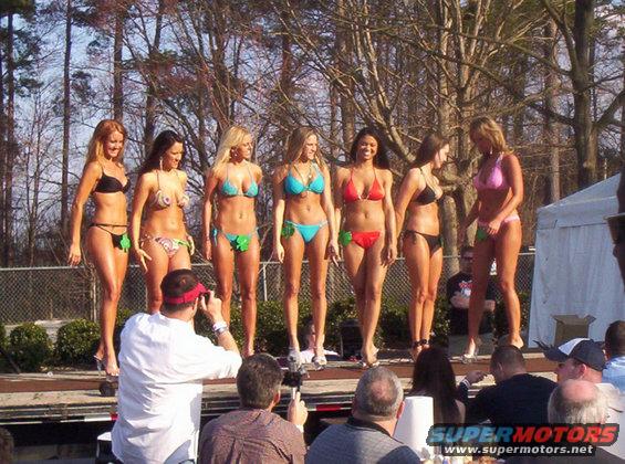 Women in bikinis on a stage with a photographer in the foreground