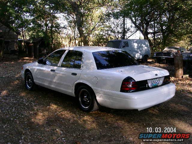 White 2001 Ford Crown Victoria parked outdoors with a van and another vehicle in the background