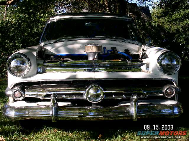 White 1954 Ford Crestline with hood open, showing engine and chrome grille