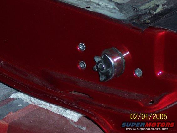 Close-up of a car's interior door latch mechanism, showing chrome and red paint