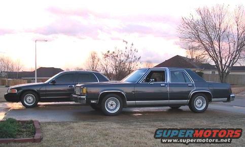 Two dark sedans, one 1985 Ford Crown Victoria LTD, parked side-by-side