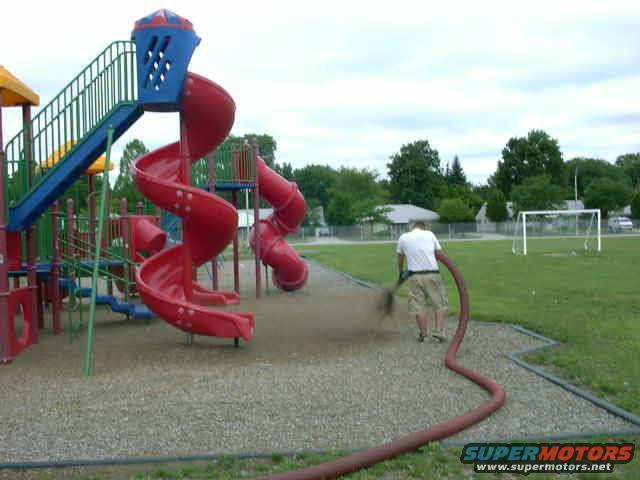 Playground slide with a person watering the ground around it