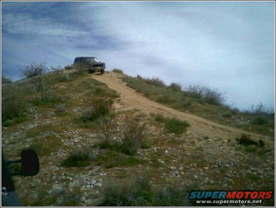1999 Ford F-250 driving up a dirt hill in a desert landscape
