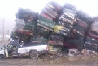 pile of crushed cars with a pickup truck in front