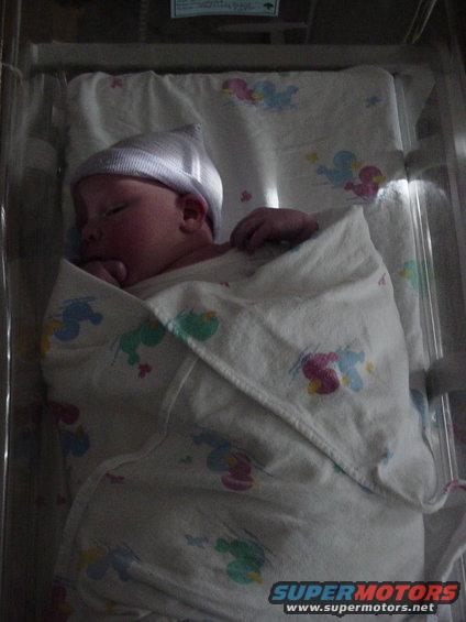 Newborn baby in a hospital bassinet wearing a cap