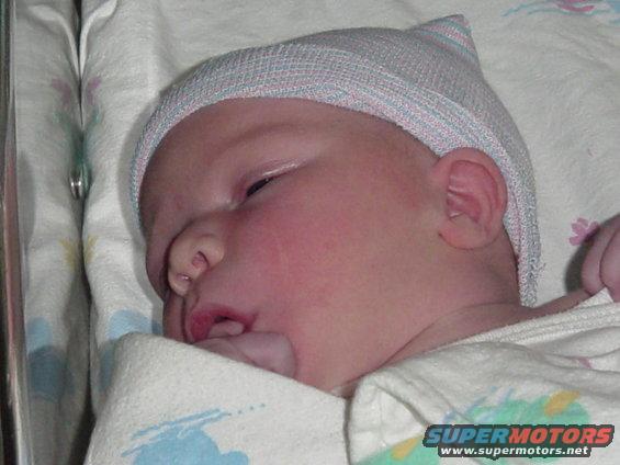 Newborn baby wearing a hospital hat and wrapped in a blanket
