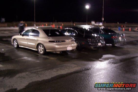 Gold 1998 Mercury Sable sedan, rear view, parked on wet asphalt at night