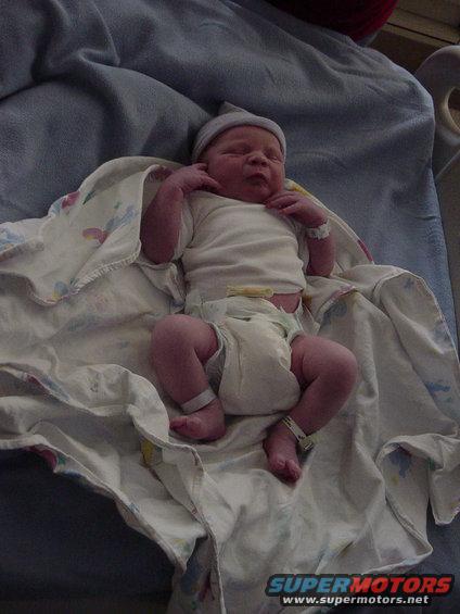 Newborn baby wearing a hat and diaper, wrapped in a blanket