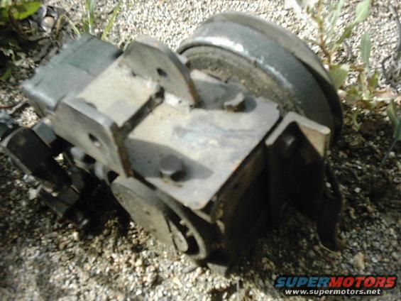 Close-up of a metal automotive brake caliper assembly resting on gravel