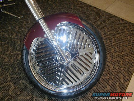 Close-up of a motorcycle's custom chrome wheel and maroon fender