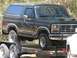 1986 Ford F-350 - A black Ford Bronco is loaded onto a trailer, viewed from the front three-quarter angle.