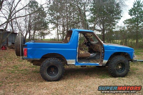 1987 Ford Bronco, blue, with spare tire mounted on rear door, interior visible