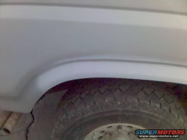 Close-up of a vehicle's rear wheel well and tire. Watermark reads SUPERMOTORS.NET