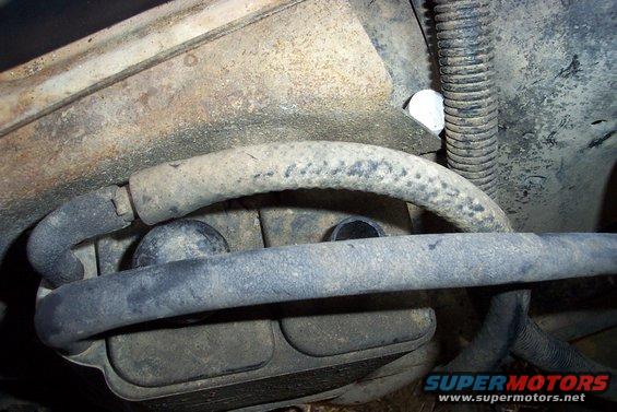 Close-up of engine hoses and metal components, some with rust and grime
