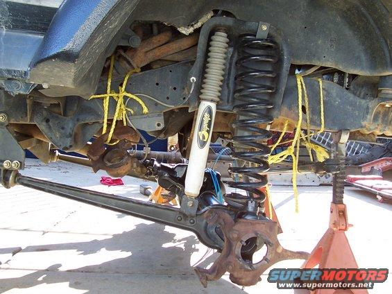 Front axle and suspension parts, including shock absorber and coil spring, held by yellow rope