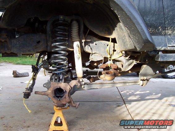 Front suspension disassembled, showing coil spring, shock, and steering linkage on jack stands