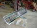 1995 Ford Bronco - A chrome grille is laid out on a concrete floor next to plastic packaging.
