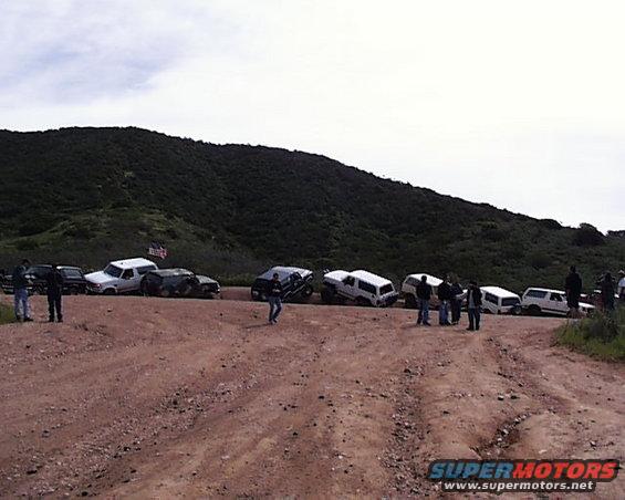 Several SUVs parked on a dirt road, some at an angle