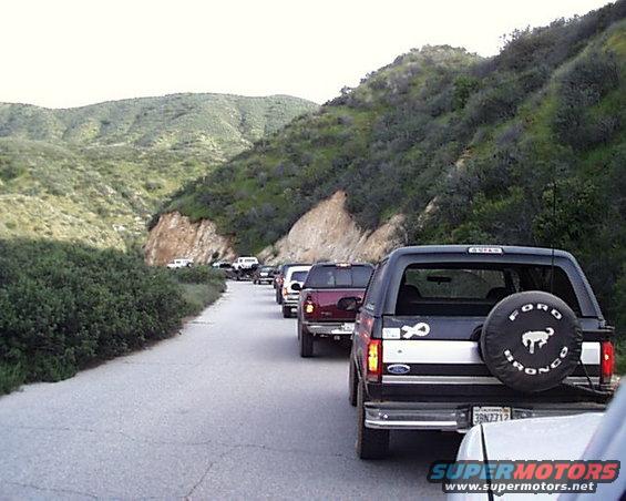 Line of SUVs on a road, including a 1993 Ford Bronco with spare tire cover