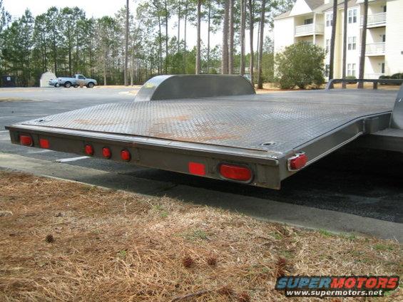 Flatbed trailer with lights on the back. A pickup truck is parked in the background