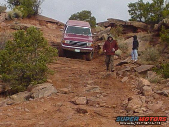 Maroon van on rocky trail, front view. Appears to be from the 1980s