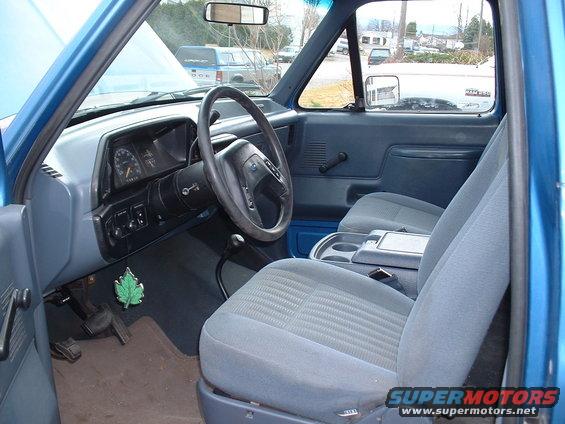 Blue Ford Bronco interior with grey cloth seats, dashboard, steering wheel, and center console. A 'Supermotors.net' watermark is visible