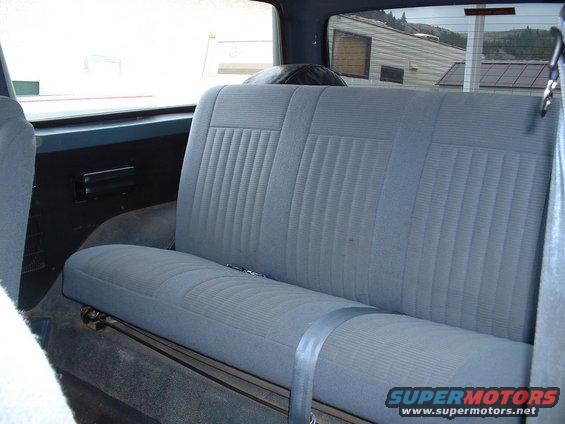 Interior rear seat of a vehicle with blue fabric upholstery and a seatbelt