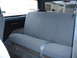 1990 Ford Bronco - The rear interior of a vehicle, showing the blue fabric seat and seatbelt, with a view out the back window.