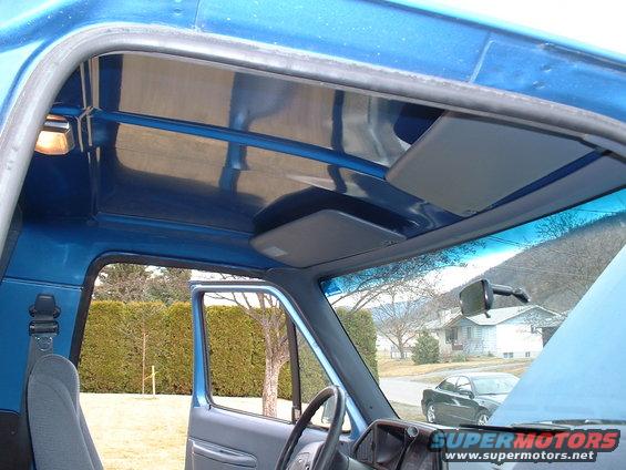 view from inside blue truck, looking out passenger side door, shows dashboard and exterior houses