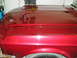 1967 Ford Mustang - Close-up of a shiny red car's hood and fender, showing reflections and a portion of the tire.