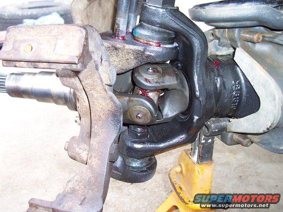 Close-up of front axle and suspension components with grease. Part number visible