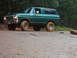 1978 Ford Bronco - This green 1978 Ford Bronco is seen off-road on a dirt path surrounded by trees.