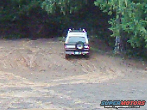 1978 Ford Bronco parked on dirt road with trees in background
