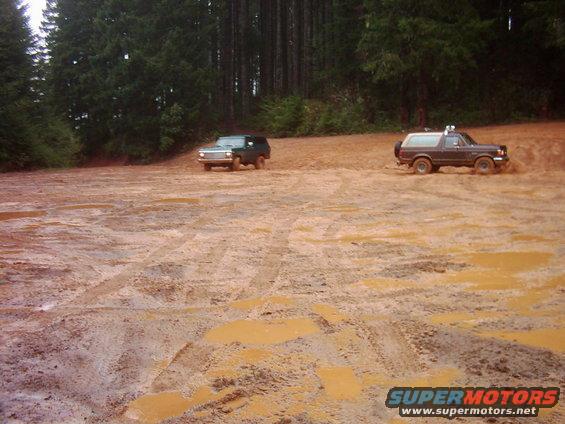 Dark brown Ford Bronco driving through mud, side view