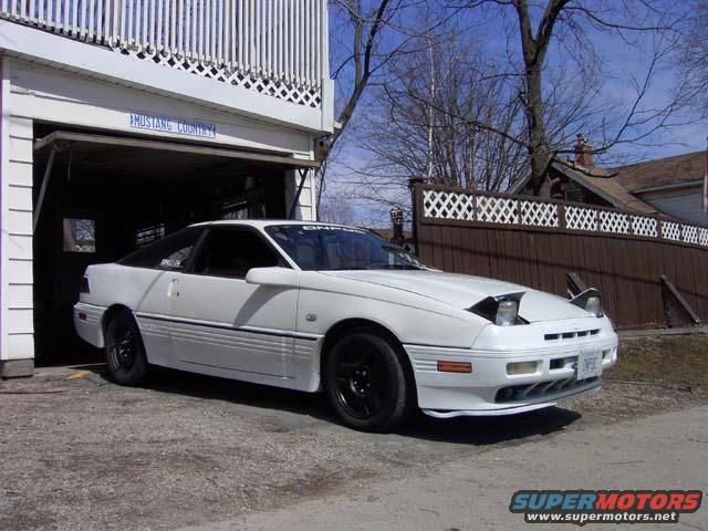 1989 Ford Probe parked outside a garage, pop-up headlights are up