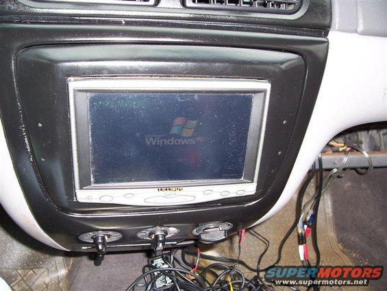 Aftermarket car stereo displaying Windows XP logo, with visible wiring