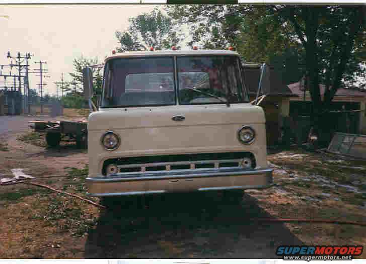 Cream-colored Ford truck front view, chrome grille, round headlights, parked outdoors