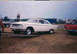1957 Ford Deluxe - A white 1963 Ford Galaxie coupe is positioned on a trailer at an outdoor event.