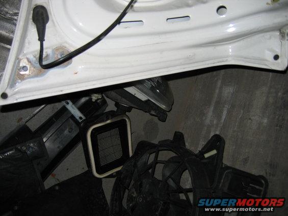 White car door interior with black wiring and disassembled car parts including a fan and headlight