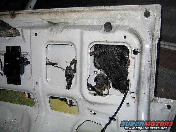 Inside of a car door showing the lock and window mechanisms. Some insulation is visible