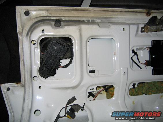 White car door interior with visible wiring and a black actuator mechanism