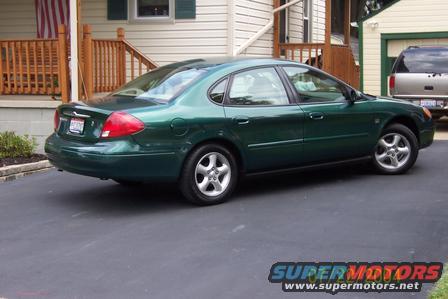 Green 2000 Ford Taurus sedan parked on asphalt, rear-left quarter view