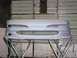 1994 Ford Probe - Unpainted car bumper on a stand in front of a corrugated metal wall.