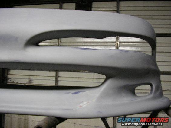 primer-coated car bumper with two large openings and a smaller fog light opening
